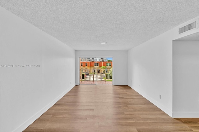 spare room featuring light hardwood / wood-style floors and a textured ceiling