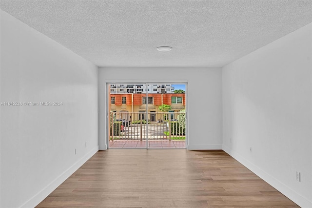 unfurnished room with a textured ceiling and light wood-type flooring