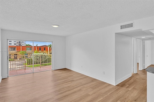 unfurnished room with light hardwood / wood-style flooring and a textured ceiling