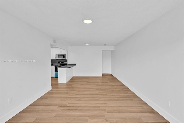 unfurnished living room with a textured ceiling and light wood-type flooring