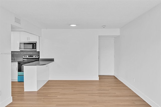 kitchen with appliances with stainless steel finishes, a textured ceiling, light hardwood / wood-style flooring, and white cabinets