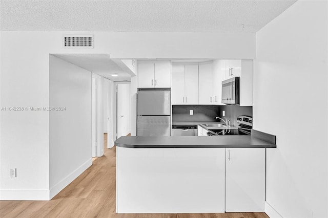 kitchen featuring sink, light hardwood / wood-style flooring, white cabinetry, stainless steel appliances, and kitchen peninsula