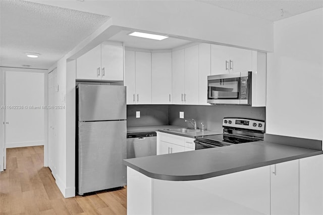 kitchen featuring white cabinetry, light hardwood / wood-style flooring, a textured ceiling, appliances with stainless steel finishes, and kitchen peninsula