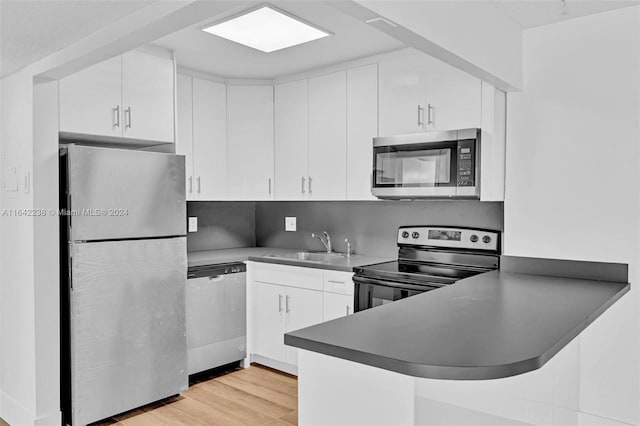 kitchen with stainless steel appliances, white cabinetry, sink, and light hardwood / wood-style flooring