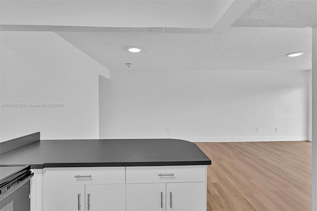 kitchen with white cabinetry, light hardwood / wood-style floors, and a textured ceiling