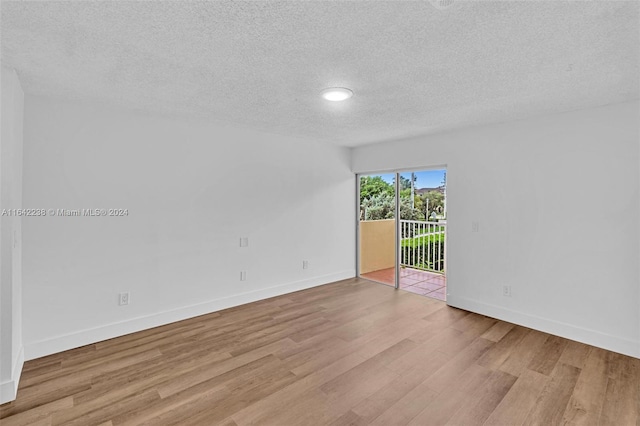 spare room featuring light hardwood / wood-style floors and a textured ceiling