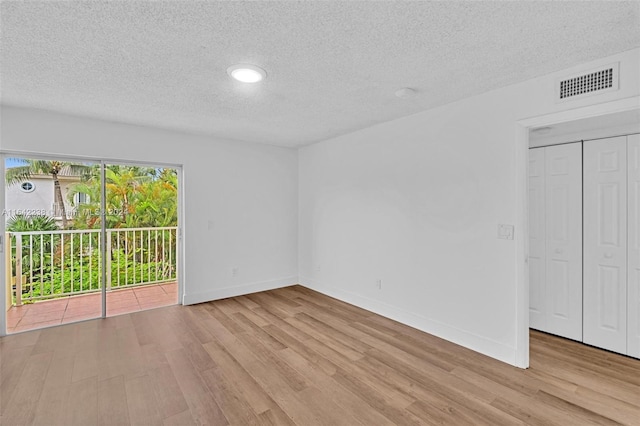 unfurnished room featuring light hardwood / wood-style flooring and a textured ceiling