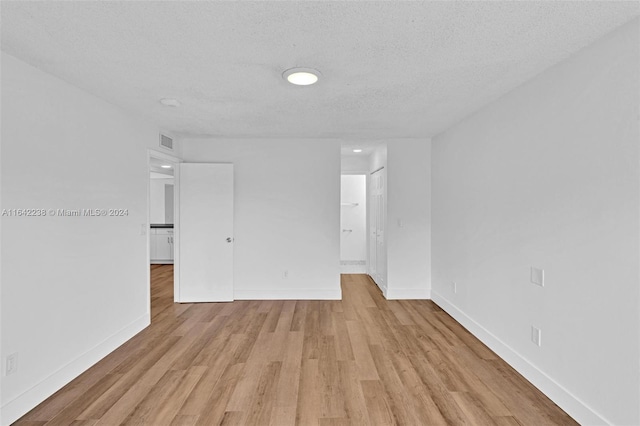 empty room featuring light hardwood / wood-style flooring and a textured ceiling