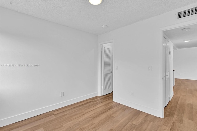 unfurnished room featuring light hardwood / wood-style flooring and a textured ceiling