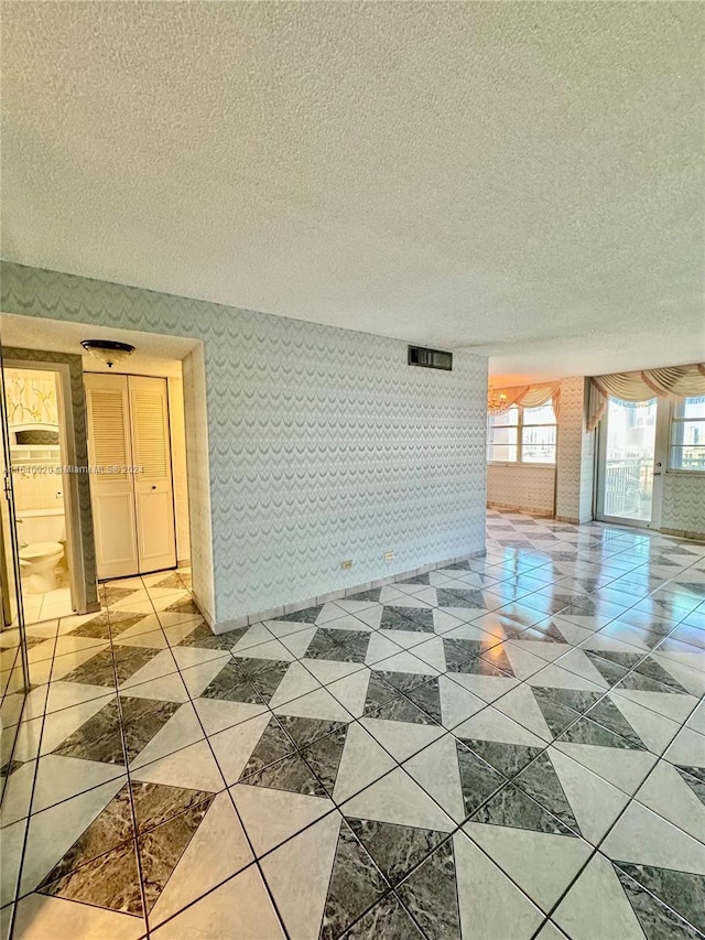 unfurnished living room featuring a textured ceiling and light tile patterned flooring