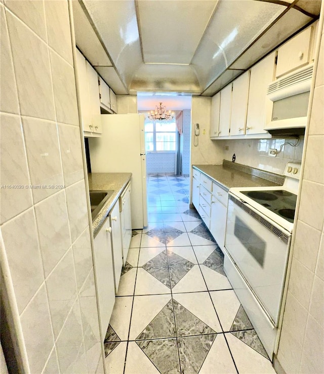 kitchen featuring light tile patterned floors, a notable chandelier, white appliances, and white cabinets