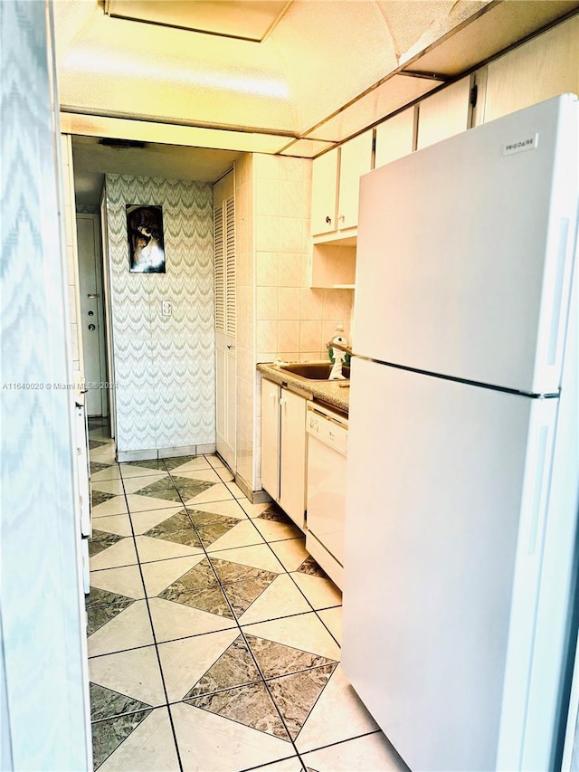 kitchen featuring backsplash, white cabinets, sink, light tile patterned flooring, and white appliances