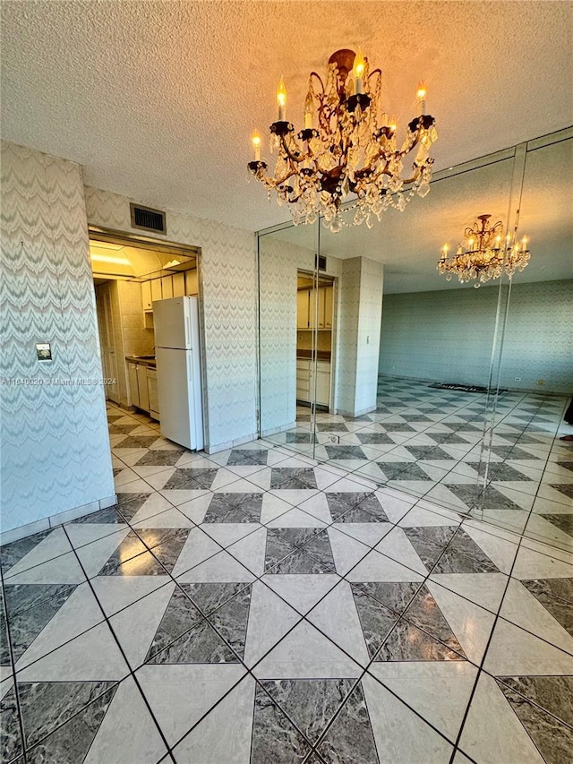 interior space featuring a textured ceiling, light tile patterned flooring, and an inviting chandelier