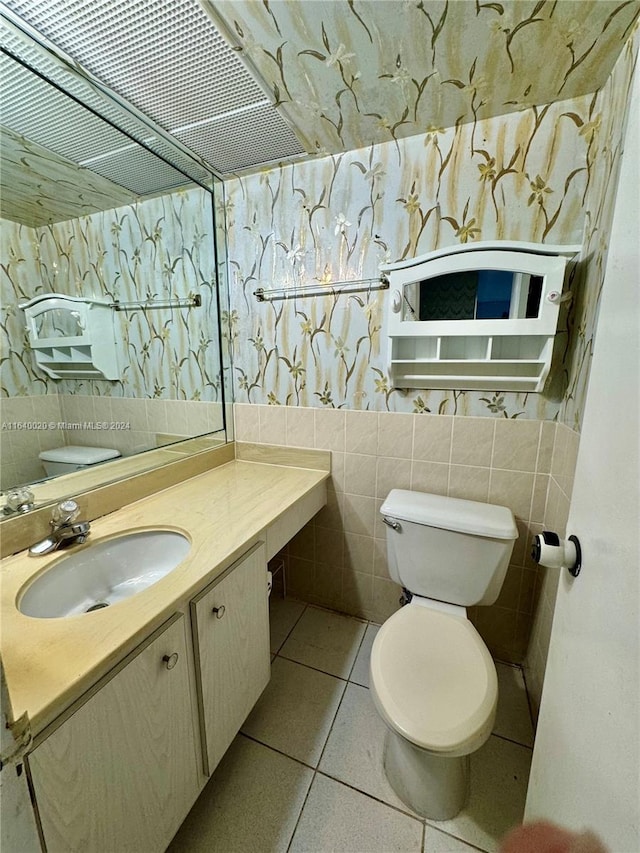 bathroom featuring tile patterned flooring, tile walls, toilet, and vanity