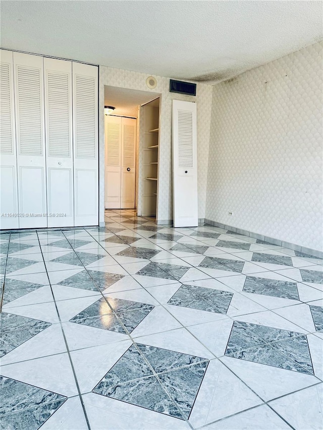 interior space featuring a textured ceiling, a closet, and light tile patterned floors