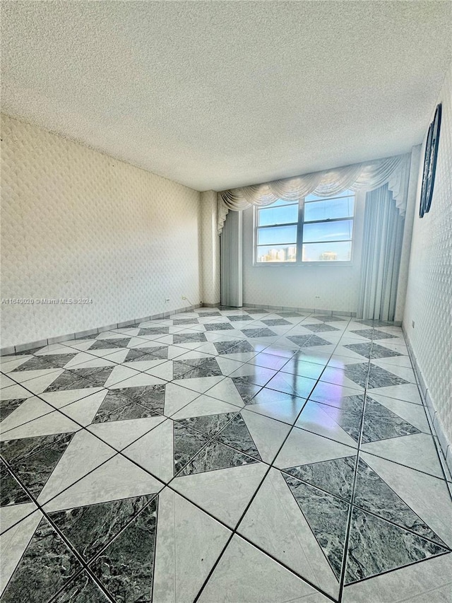 spare room featuring light tile patterned floors and a textured ceiling