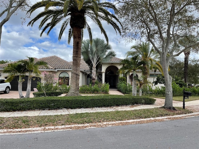 mediterranean / spanish-style home featuring stucco siding, driveway, and a tile roof