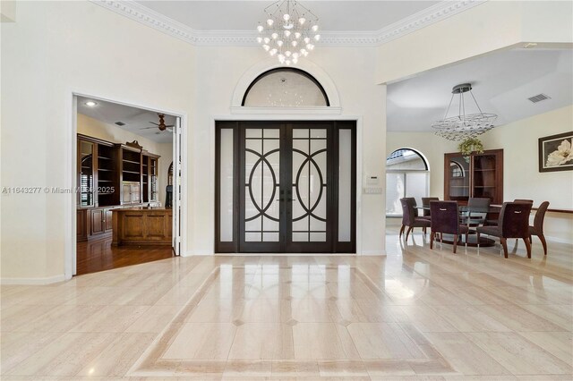 unfurnished living room with french doors, a notable chandelier, and ornamental molding