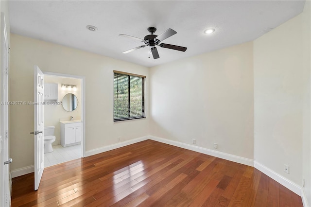 unfurnished bedroom featuring ceiling fan, light wood-type flooring, sink, and ensuite bath