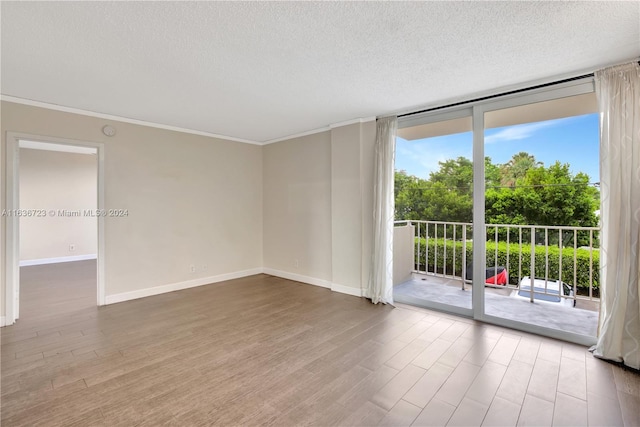 empty room with a wealth of natural light, light hardwood / wood-style flooring, floor to ceiling windows, and a textured ceiling