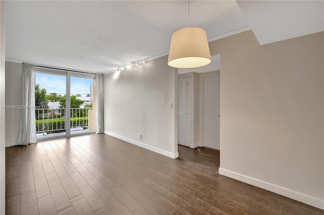 spare room with rail lighting, a textured ceiling, and floor to ceiling windows