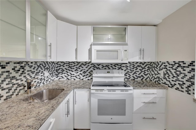 kitchen with white cabinets, decorative backsplash, sink, and white appliances