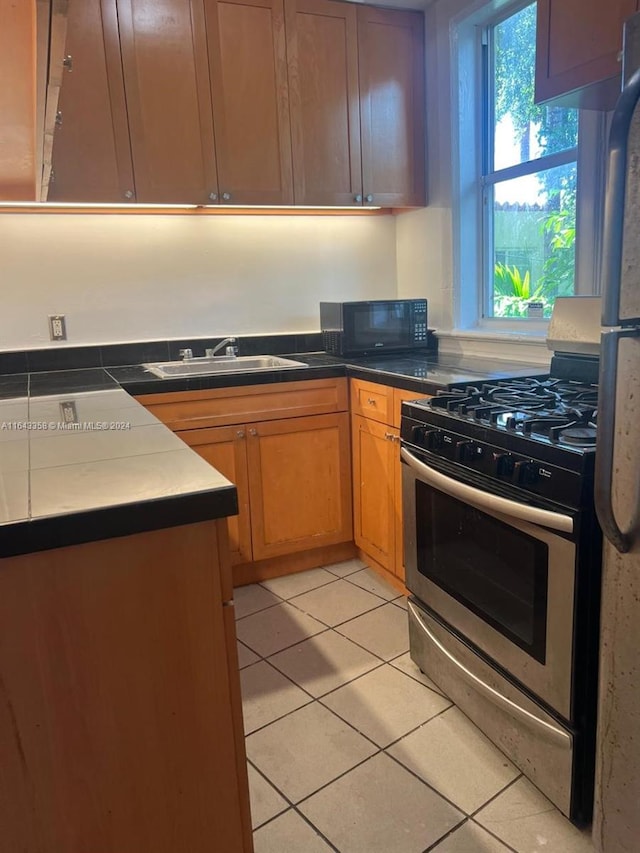 kitchen with sink, appliances with stainless steel finishes, and light tile patterned floors