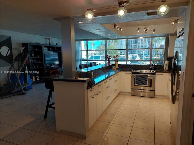 kitchen with light tile patterned floors, appliances with stainless steel finishes, white cabinetry, kitchen peninsula, and rail lighting