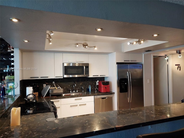 kitchen with track lighting, tasteful backsplash, sink, appliances with stainless steel finishes, and white cabinets