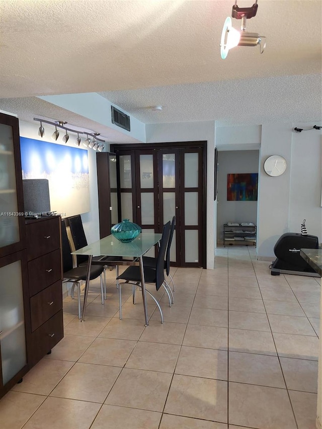 tiled dining area with a textured ceiling and rail lighting