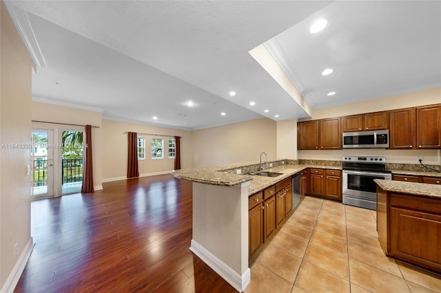 kitchen with kitchen peninsula, light stone counters, stainless steel appliances, crown molding, and sink