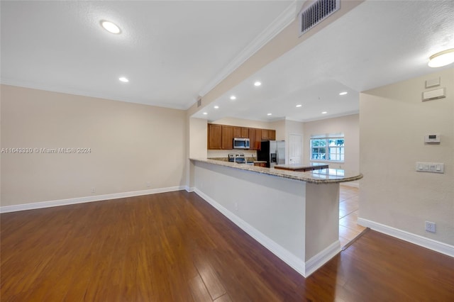 kitchen featuring kitchen peninsula, light stone counters, a textured ceiling, stainless steel appliances, and wood-type flooring