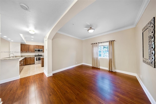 unfurnished living room featuring crown molding, sink, a textured ceiling, and light wood-type flooring