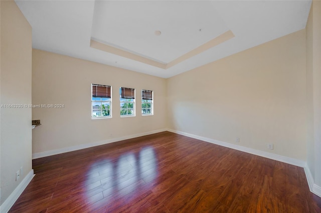 spare room featuring a raised ceiling and dark hardwood / wood-style floors