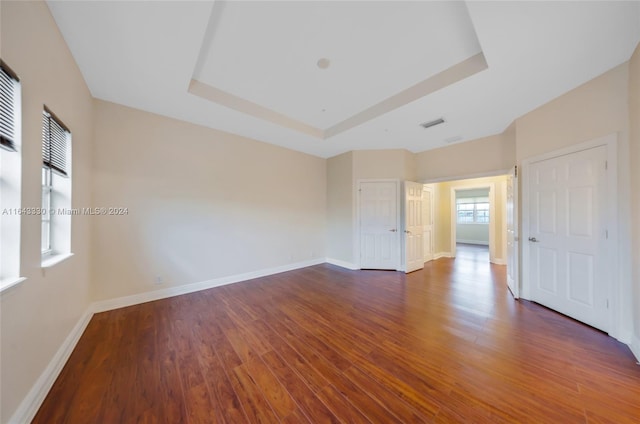 empty room featuring a tray ceiling and dark hardwood / wood-style floors