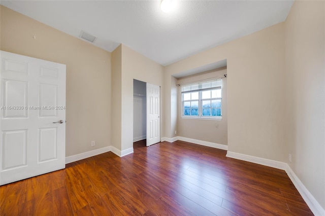 unfurnished bedroom with dark wood-type flooring and a closet