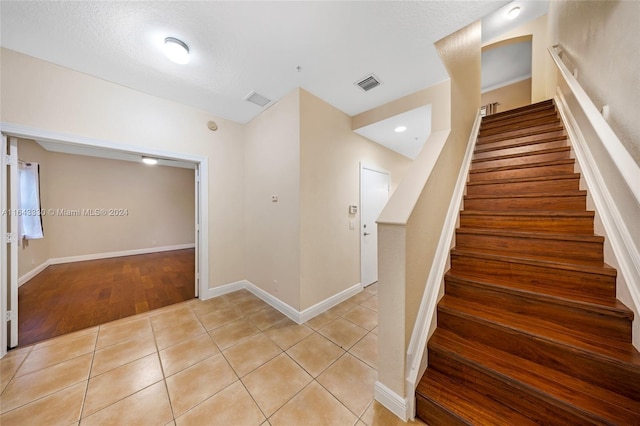 staircase featuring tile patterned floors and a textured ceiling