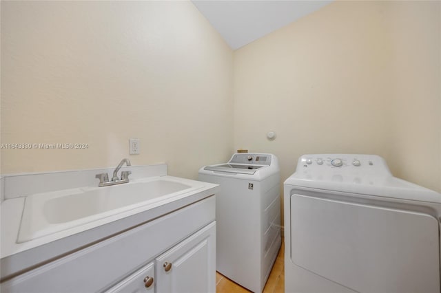 laundry room featuring washer and dryer, cabinets, sink, and light hardwood / wood-style flooring