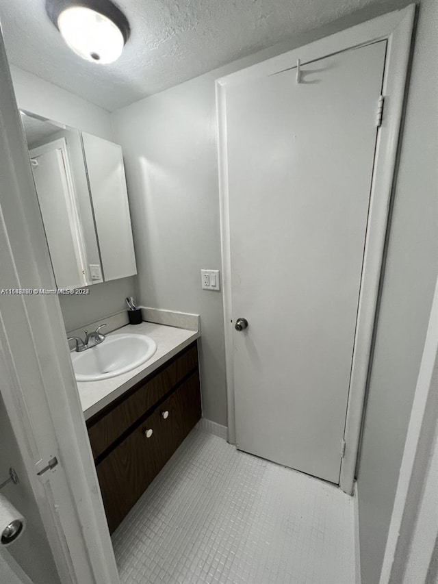 bathroom featuring tile patterned flooring, a textured ceiling, and vanity