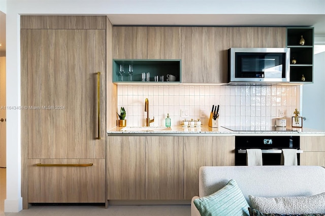 bar with light stone countertops, appliances with stainless steel finishes, backsplash, and sink