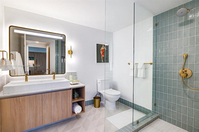 bathroom featuring tile patterned flooring, vanity, tiled shower, and toilet