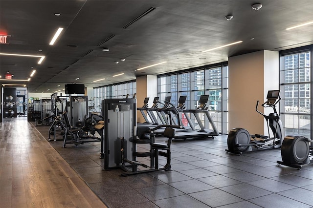 gym featuring a wall of windows, plenty of natural light, and dark hardwood / wood-style floors