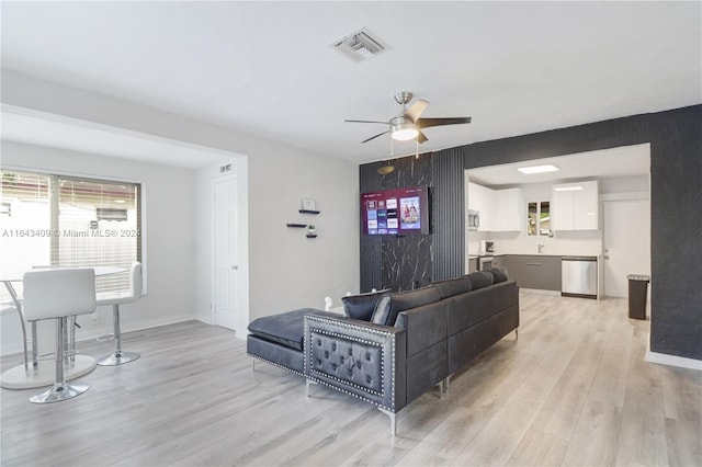 living room with sink, light hardwood / wood-style flooring, and ceiling fan