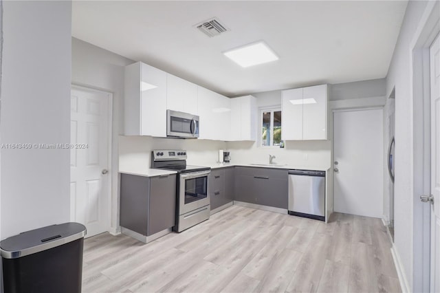 kitchen featuring stainless steel appliances, sink, light wood-type flooring, white cabinets, and gray cabinets