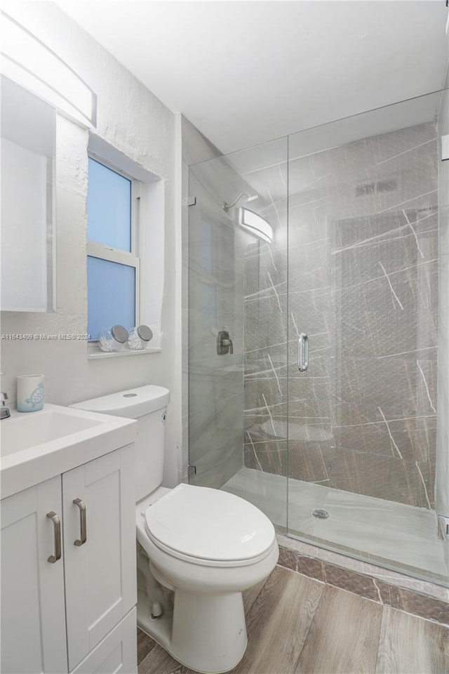 bathroom featuring toilet, walk in shower, vanity, and wood-type flooring