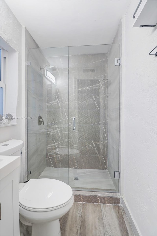 bathroom with an enclosed shower, toilet, hardwood / wood-style floors, and vanity