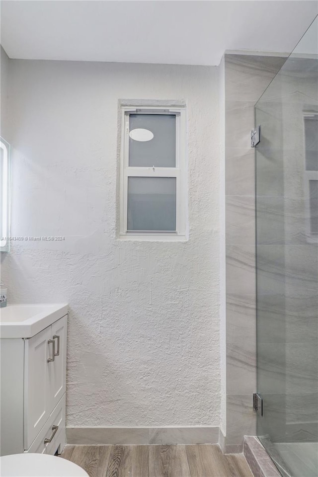 bathroom featuring a shower with shower door, toilet, hardwood / wood-style flooring, and vanity