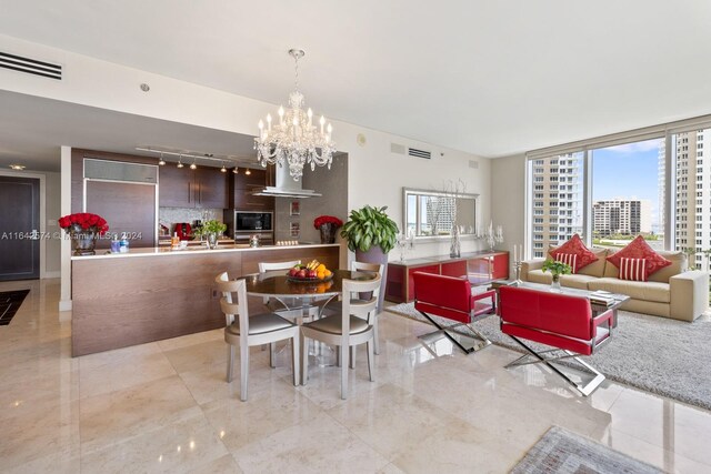 dining area featuring light tile patterned floors, rail lighting, and a notable chandelier