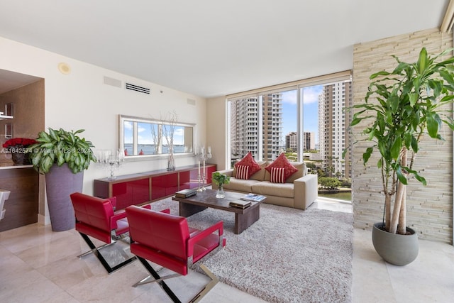 living room featuring a view of city, a wall of windows, plenty of natural light, and visible vents