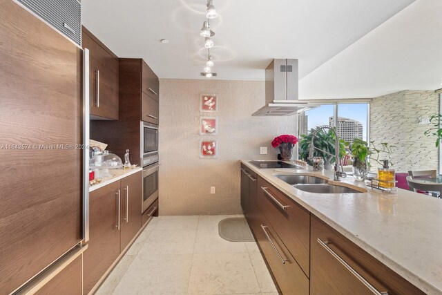 kitchen with light tile patterned flooring, sink, rail lighting, stainless steel appliances, and island range hood